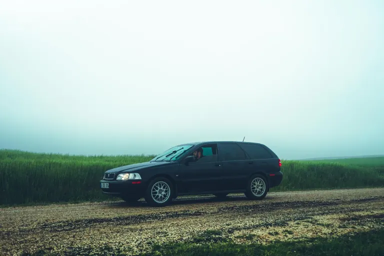 Mörk kombibil parkerad på en grusväg vid ett grönt fält, en bild för billån och bilköp