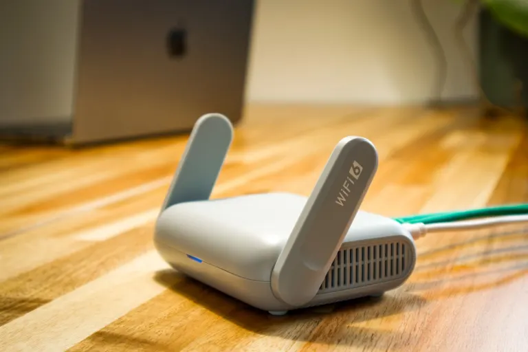 Vit wifi-router på ett skrivbord i trä i hemmakontoret, en bild för att jämföra bredband