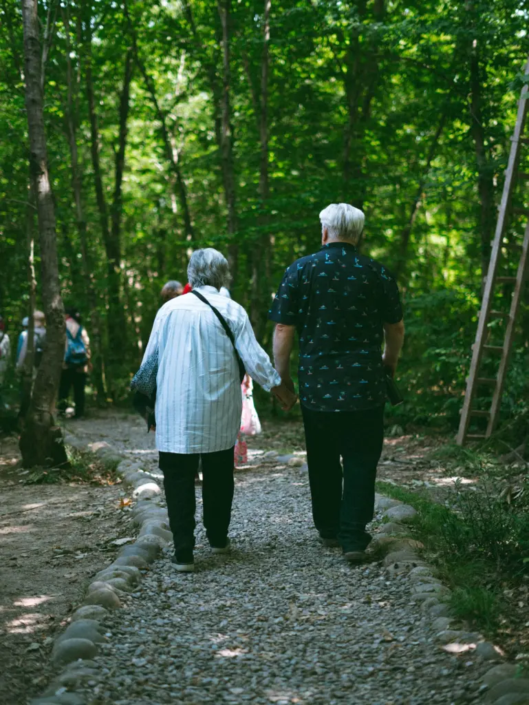 Äldre par går hand i hand på en grusstig i skogen, när arbetslivet är slut och man går i pension