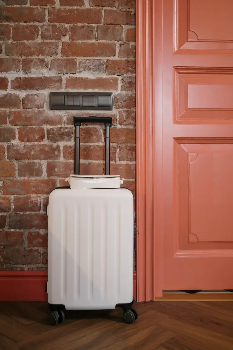 Packad resväska som står vid en stängd dörr inomhus inför en resa