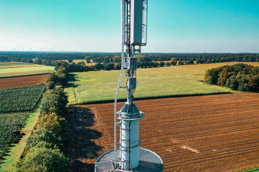 Mobilmast med antenner ovanför åkrar och skogsdungar på landsbygden, där täckningen skiljer sig mellan mobilnäten