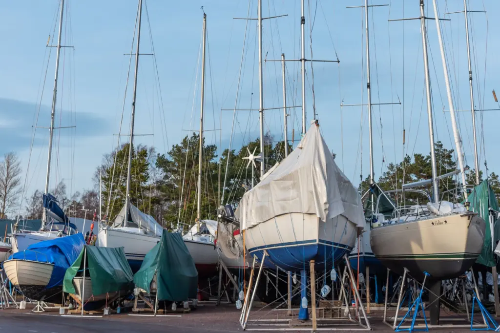 Segelbåtar på bockar och vaggor med presenningar på en vinteruppställning i hamnen, där båten ska vara pallad, stöttad och täckt