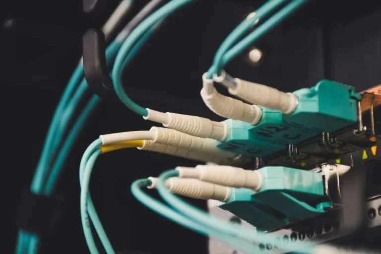 Turkosa fiberkablar inkopplade i en switch i ett nätverksskåp, fibernätet i huset avgör om du kan välja bredbandsleverantör själv