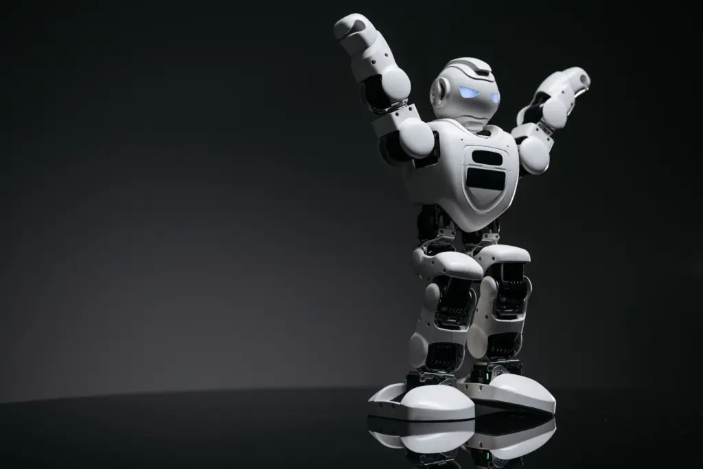 Vit leksaksrobot med blå lysande ögon sträcker upp armarna mot en mörkgrå bakgrund