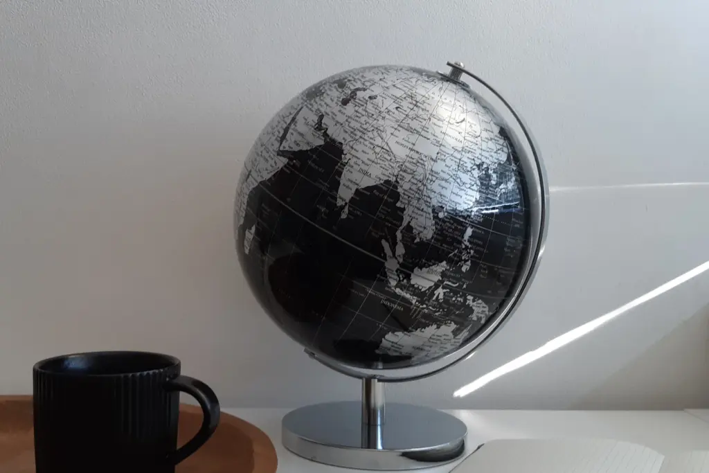 Jordglob och kaffekopp på ett ljust skrivbord, global fond eller Sverigefond