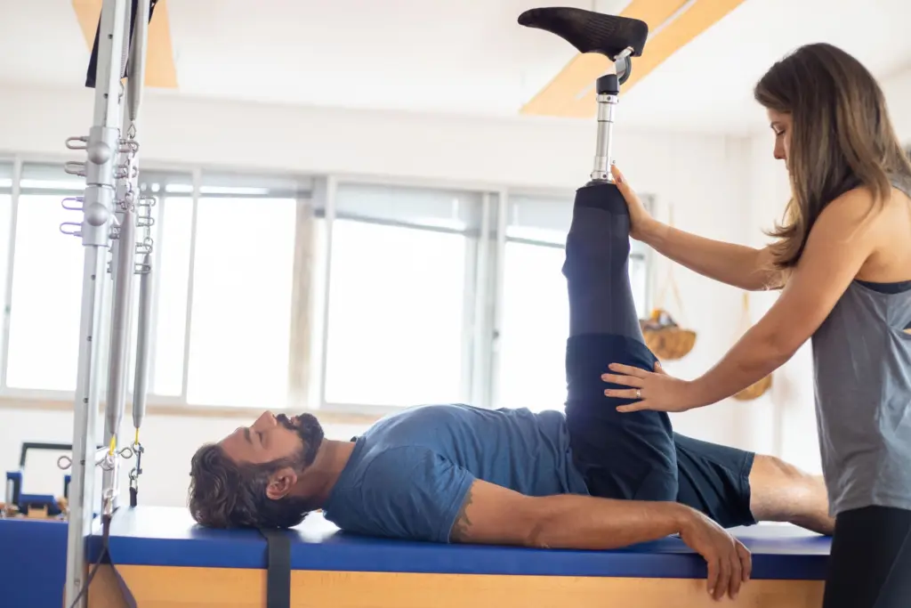 Man med benprotes tränar med en fysioterapeut, rehabilitering efter en skada som gett bestående invaliditet