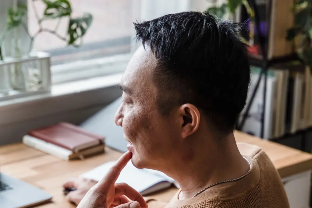 Man sitter vid skrivbordet hemma med handen mot hakan och funderar, inför valet av privatlån och vilken ränta han kan få