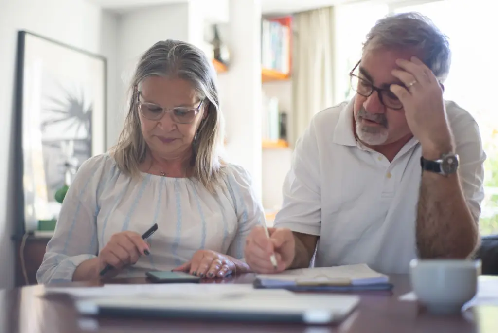 Äldre par räknar på ekonomin vid köksbordet med papper och kaffe, om skatten på pension 2026