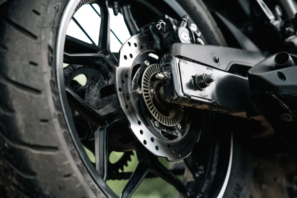 Närbild på bakhjulet och bromsskivan på en motorcykel, där ett godkänt skivlås sitter