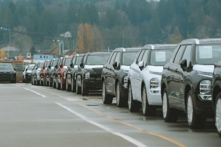 Rader av nya bilar parkerade på en bilhandlares uppställningsplats en mulen höstdag, en bild för att jämföra billån