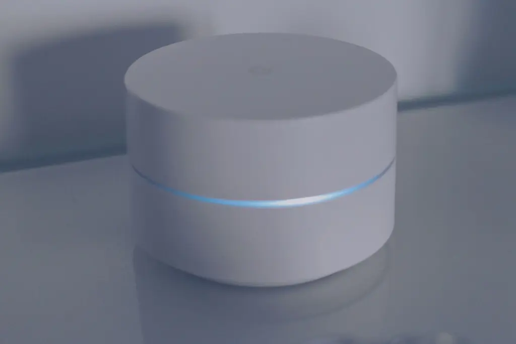Vit trådlös router med ett blått ljus på en hylla hemma