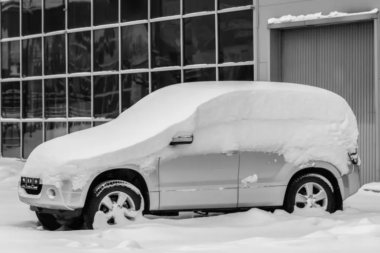 Bil täckt av tjock snö som står parkerad och oanvänd utomhus en vinterdag