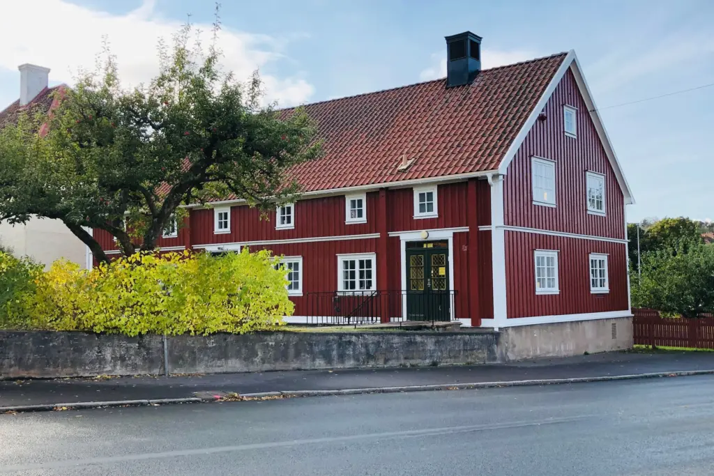 Rött trähus med vita knutar vid en villagata i Sverige, bostaden som säkerhet för ett utökat bolån