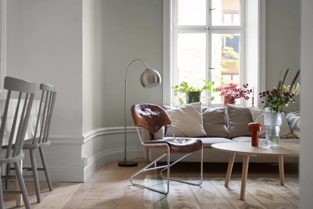 Ljust skandinaviskt vardagsrum med soffa och fönsterljus, hemmet som hemförsäkringen skyddar