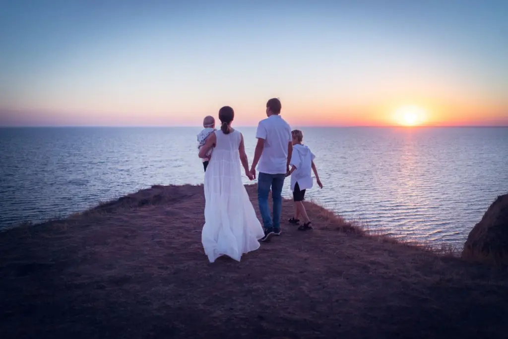 Familj står vid havet och ser på solnedgången