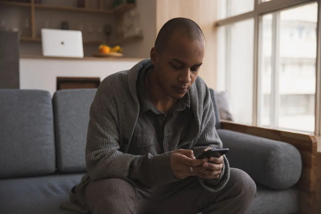 Man i soffan läser låneerbjudanden i mobilen efter en ansökan via en låneförmedlare