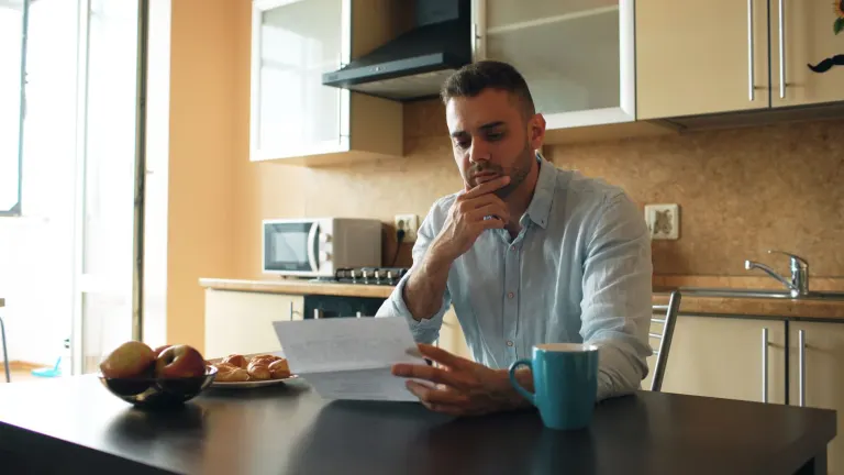 Man läser ett brev vid köksbordet och funderar på ett privatlån till rätt ränta